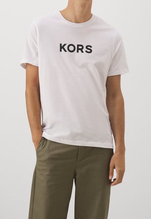 T-shirt en coton blanc avec un logo noir "KORS" au centre. Col rond, manches courtes et coupe décontractée.