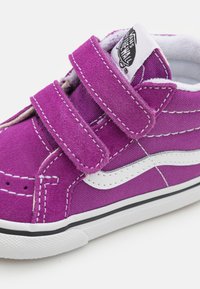 Lila Leinenschuh mit weißen Akzenten und Klettverschlüssen, ausgestattet mit einem gestickten Design und einer schwarzen Gummisohle.