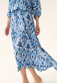 Modrá šaty s potiskem vyrobené z lehkého materiálu, s volným střihem, dlouhými rukávy a utaženým pasem.