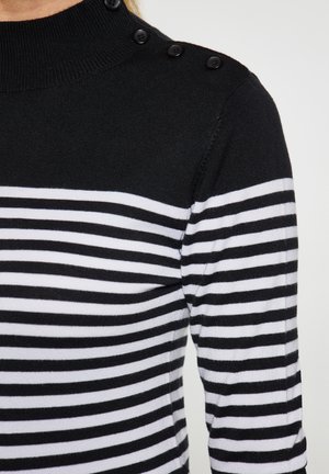 Gestreifter Pullover in Schwarz-Weiß mit hohem Kragen, ausgestattet mit schwarzen Knöpfen an der Schulter und einer weichen Stricktextur.