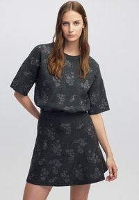Donkergrijze gebreide tweedelige set bestaande uit een top met korte mouwen en een uitlopende rok, beide versierd met een subtiel bloemenpatroon.