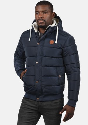 Navy puffer jacket with a hood, featuring a fleece lining, button accents, and ribbed cuffs. Padded sections for insulation and warmth.