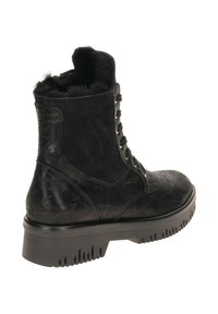 Schwarzer Knöchelstiefel aus strukturiertem Leder mit Schnürung vorne, einer fellartigen Innenauskleidung am Kragen und einer klobigen Gummisohle.