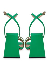 Sandalias de tacón verde con un ancho tacón texturizado y correas entrelazadas. Diseño de punta abierta con una suela lisa y sin agarre.