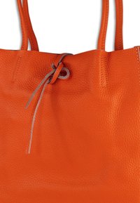Oranje leren tote bag met een gestructureerde afwerking, voorzien van een trekkoordsluiting en twee schouderbanden. Geen extra versieringen.