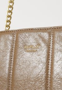 Bruine nep-lederen handtas met een gequilt ontwerp, gouden hardware en een gouden "REPLAY SINCE 1981" logo aan de voorkant.