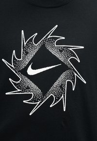 Μαύρο ύφασμα με λευκό λογότυπο Nike σε σχήμα Swoosh μέσα σε ένα κυκλικό σχέδιο με μυτερές ακμές, φτιαγμένο από υφασμένα και τεθριμμένα μοτίβα.