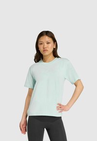 Camiseta de manga corta azul claro hecha de una tela suave. Presenta un cuello redondeado y un ajuste relajado. Se lleva con leggings negros.