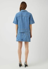 Jeansjacka med korta ärmar och kort design, ihop med en jeans mini kjol. Ljusblå färg, sydda detaljer och två bakfickor.