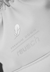 Weißer Stoff mit geprägtem Branding, einschließlich "reusch" und "Premium Down", sowie einem subtilen Blatt-Logo. Glatte Textur mit Nähdetails.
