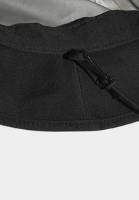 Melns auduma cepure ar tekstūrētu virsmu, kas aprīkota ar savilces aizdari un mīkstu iekšējo oderi. Šūti mali un smalks detaļas uz kroņa.