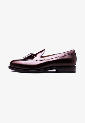 Braune Lederloafers mit glänzendem Finish, ausgestattet mit einer markanten dekorativen Schnalle und einer Steppnaht entlang der Seiten sowie einer runden Zehenform.