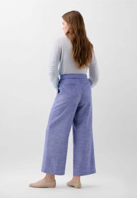 Pull bleu clair, ample, associé à un pantalon lavande taille haute à jambes larges présentant une texture subtile et des détails de poches.