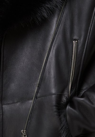 Černá kožená bunda s měkkým koženým límcem, diagonálními zipovými kapsami a texturovanou kůží. Design je slim-fit s decentním prošíváním.