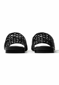 Μαύρα σανδάλια τύπου slip-on με φαρδιές πλεγμένες λουρίδες και επίπεδες σόλες, εμφανιζόμενα από μπροστά σε λευκό φόντο.