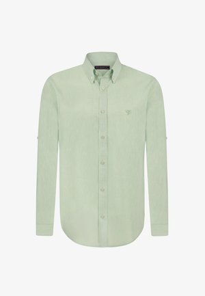 Camisa de manga larga verde claro con cuello abotonado, textura sutil, un pequeño logo bordado en el pecho y dobladillo redondeado.
