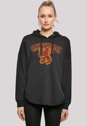 Svart hettegenser med et Gryffindor-løvegrafikk i burgunder og gull. Løs passform med lange ermer og en avrundet kant.