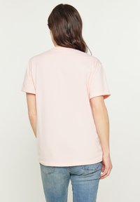 Lyserød bomulds t-shirt med korte ærmer og en klassisk rund halsudskæring, glat tekstur og et simpelt, udekoreret design.