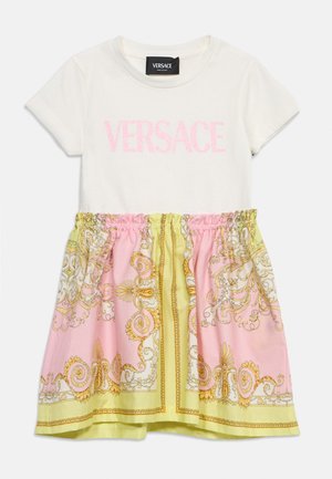 Robe blanche à manches courtes avec texte rose "VERSACE" en haut et jupe froncée arborant des motifs baroques ornés en rose, jaune et or.