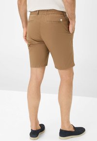Shorts marron en tissu léger avec une taille élastique, dotés de deux poches arrière et d'une texture lisse et mate.
