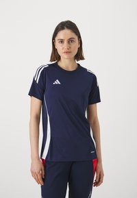 Tumesinine spordit-särk valgete küljeribade ja logoga. Lühikesed varrukad, ümmargune kaelus, valmistatud hingavast kangast aktiivsete tegevuste jaoks.