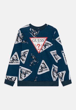 Sweatshirt bleu marine avec logos triangulaires blancs Guess répétés, bordés de rouge avec un point d'interrogation, poignets et ourlet côtelés.