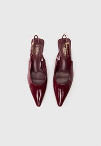 Spīdīgas tumši sarkanas, norādītā pirksta slingback plakanās kurpes ar zelta sprādžu siksnām, ar zīmolu "SIMMI London" uz mīkstinātajām zolēm.