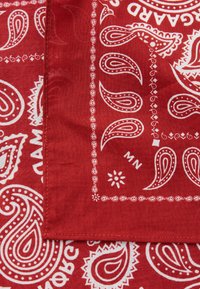 Rød bomullsbandana med hvite paisleymønstre og dekorative kanter, med en sømmet kant og et lite blomstermønster i hjørnet.