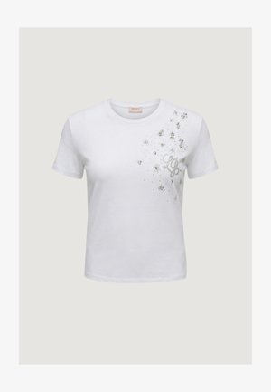 Camiseta blanca de manga corta con cuello redondo, salpicada de purpurina plateada y con detalle del logo estilizado "LG" en el lado izquierdo superior del pecho.