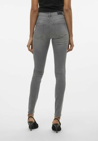 Jeans ajustados grises con una cintura alta, que cuentan con dos bolsillos traseros y costuras en contraste. Denim suave con un ligero estiramiento.