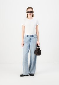 Λευκό κοντομάνικο μπλουζάκι, ανοιχτό μπλε φαρδιά τζιν παντελόνια με πουά σχέδιο, μαύρα γυαλιά ηλίου, μαύρη τσάντα χειρός με κοντές λαβές, επίπεδες παπούτσια.