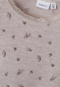 Top in cotone rosa chiaro con piccoli motivi floreali in viola scuro e verde. Presenta un colletto in pizzo scallop per un tocco di dettaglio in più.