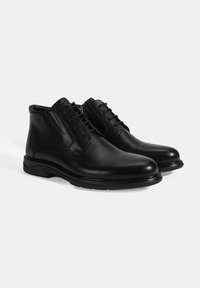 Bottines en cuir noir avec une finition lisse, dotées d'un bout arrondi, d'un laçage à l'avant et d'une semelle en caoutchouc avec des accents texturés.