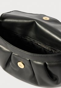 Μαύρη δερμάτινη τσάντα με καμπυλωτό σχέδιο, που διαθέτει χρυσό κούμπωμα με κουμπί και υφασμάτινες πτυχές κατά μήκος της ανοίγοντας. Το εσωτερικό είναι επενδεδυμένο με μαύρο ύφασμα.