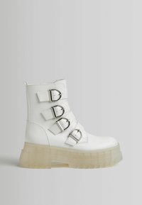 White ankle boot made of synthetic material with four adjustable buckle straps and a translucent chunky heel. Smooth texture and tailored design.