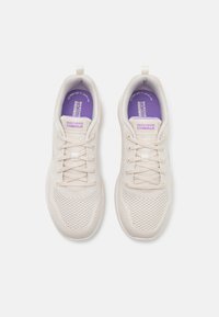 Light beige athletic shoes with a mesh upper and flat lace closure. Features a purple insole with "SKECHERS GO WALK" branding.
