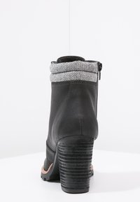 Stivaletto nero con tomaia in pelle, tacco nero a coste e colletto in maglia a spina di pesce grigia. Cerniera laterale per l'accesso. Suola testurizzata per una buona aderenza.