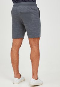 Gray shorts with a textured pattern, a back pocket, and an elastic waistband, paired with white slip-on shoes.