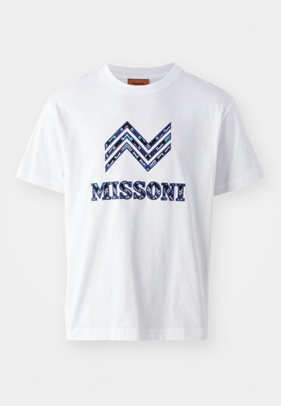 Λευκή βαμβακερή μπλούζα με γραφικό σχέδιο που παρουσιάζει μπλε και πράσινα σχέδια ζιγκ ζαγκ και τη λέξη "MISSONI" σε έντονα γράμματα στο μπροστινό μέρος.