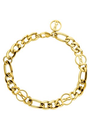 Close-up van een persoon die een beige geribd tanktop en een gouden schakelenarmband om de rechterpols draagt.