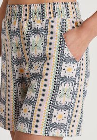 Korte gestreepte shorts met een elastische tailleband, voorzien van palmbomen, zonmotieven en geometrische ontwerpen in pastelkleuren met zwarte accenten.