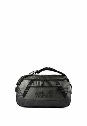 Bolsa tipo saco Jack Wolfskin en verde oscuro y negro, con correa de hombro acolchada y bolsillo frontal con cremallera sobre un fondo blanco.