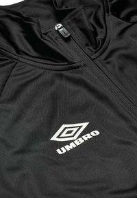 Sort sportjakke lavet af glat, letvægtsmateriale. Funktioner inkluderer en frontlynlås og hvid 'Umbro'-logo med en geometrisk form.