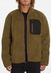 Olivgrön fleecejacka med dragkedja framtill, hög krage och ficka med svart märke. Mjuk textur med avslappnad passform och kontrasterande dragkedjedetalj.