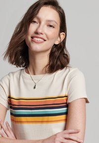 Crème t-shirt met horizontale strepen in oranje, marineblauw, groen en geel. Korte mouwen met een ronde hals. Soepele katoenen textuur.