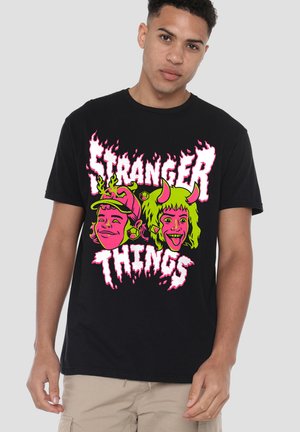 Black cotton t-shirt featuring a bold, colorful graphic that includes cartoon characters and "Stranger Things" text in pink and green.