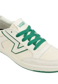 Vita och krämfärgade Vans-sneakers med gröna snören, grönt märke på sidan och grön Vans-logga på tungan.
