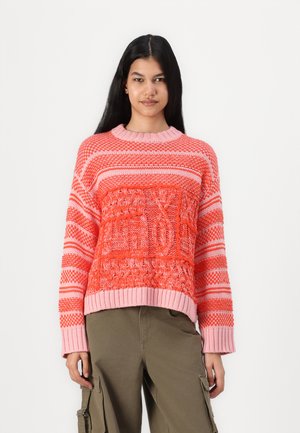 Knitted sweater in shades of pink and orange, featuring stripes and textured patterns. Loose fit with ribbed cuffs and hem.