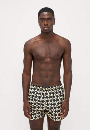 Costume da bagno neri e beige con un motivo a onde. Vita elastica per il comfort, realizzati in materiale leggero adatto per l'acqua.