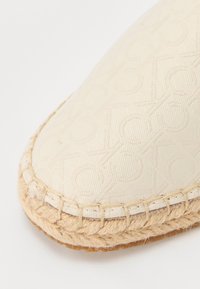 Béžové espadrilky s texturovanou tkaninou, která má jemný vzor, sisalovou podrážku a prošití kolem okraje.